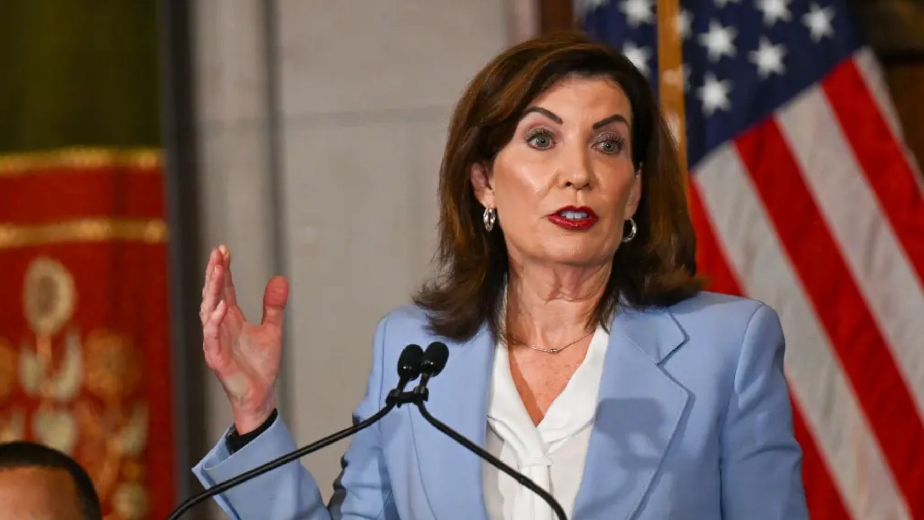 New York governor speaks at a podium as the state announces inflation refund checks of up to $400 for millions of households.