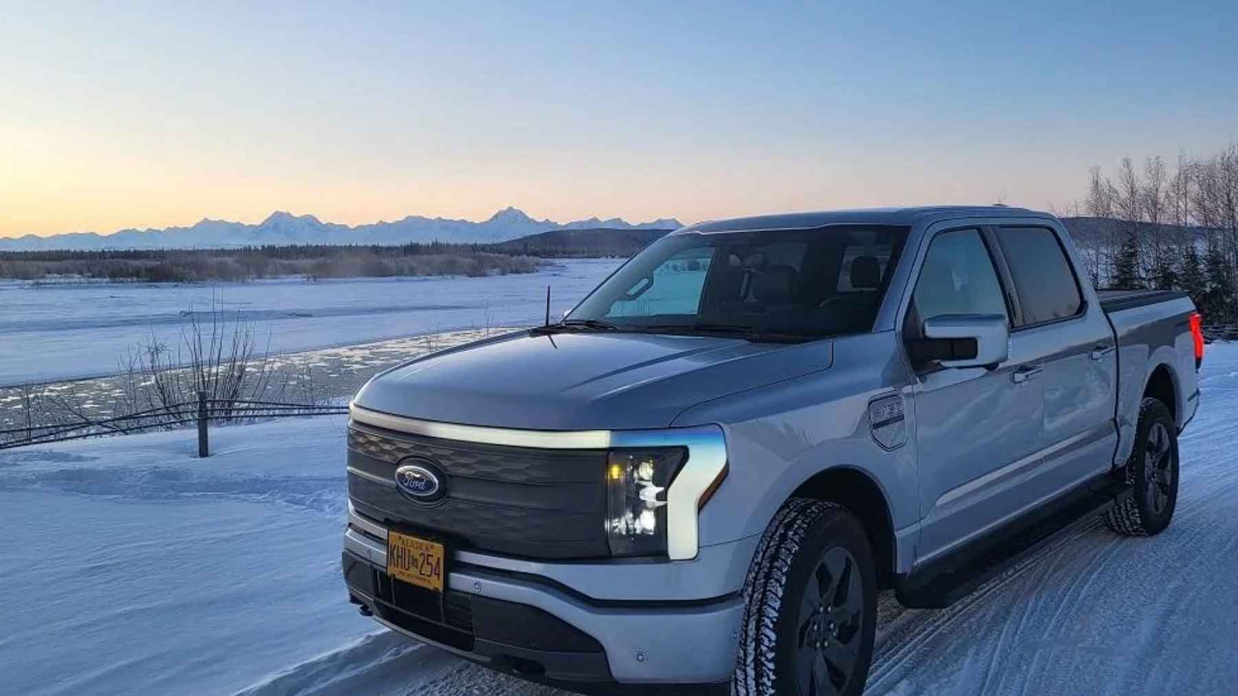 Ford F-150 Lightning electric pickup parked on a snowy road at dusk in freezing winter conditions