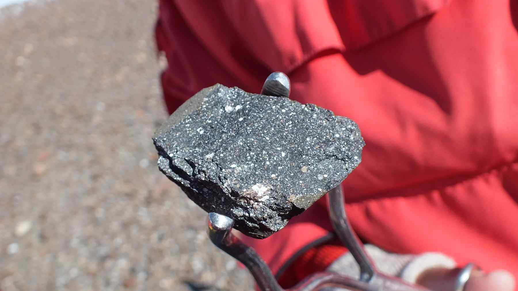 Small dark meteorite half buried in Antarctic ice, a carbonaceous chondrite studied for water and metal resources for space exploration.