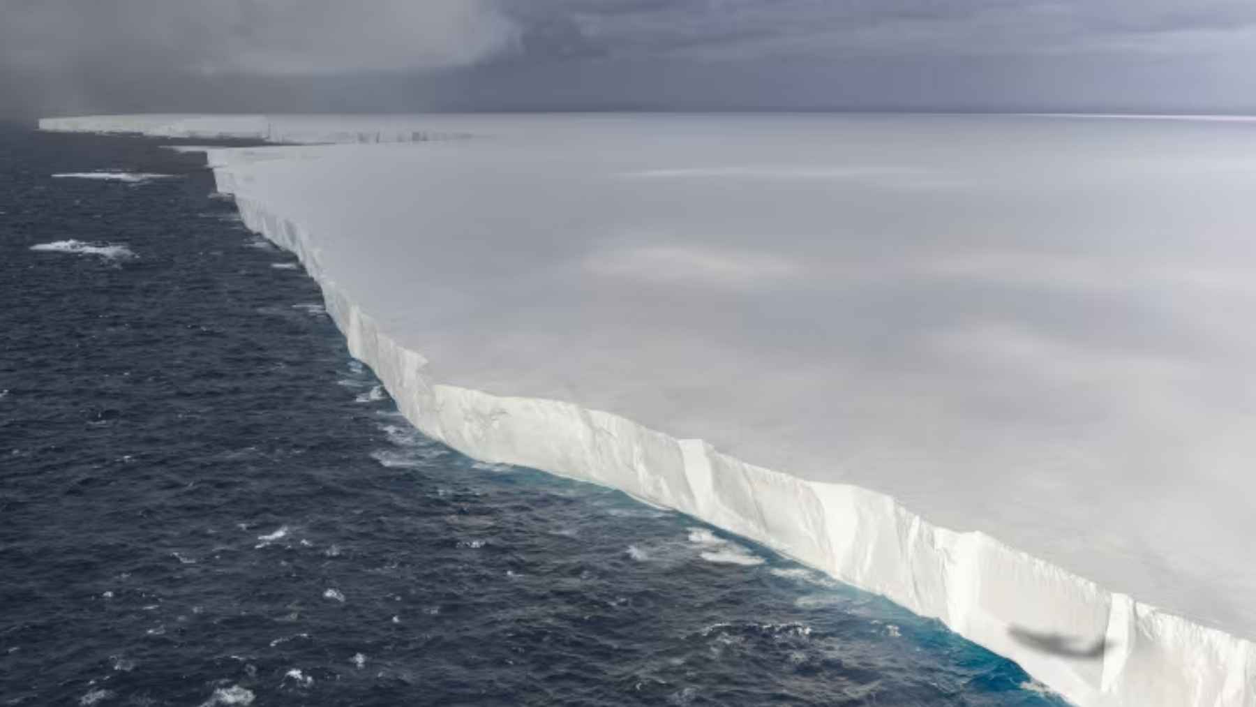 Borde del iceberg A23a flotando en el Atlántico Sur junto a aguas oscuras, bajo un cielo nublado