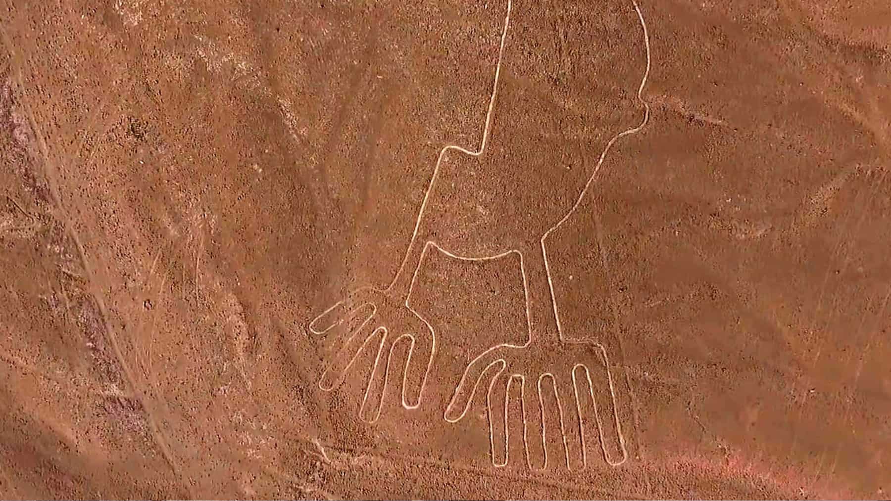 Vista aérea de un geoglifo de las Líneas de Nazca con figura antropomorfa y manos grandes trazadas sobre el desierto.