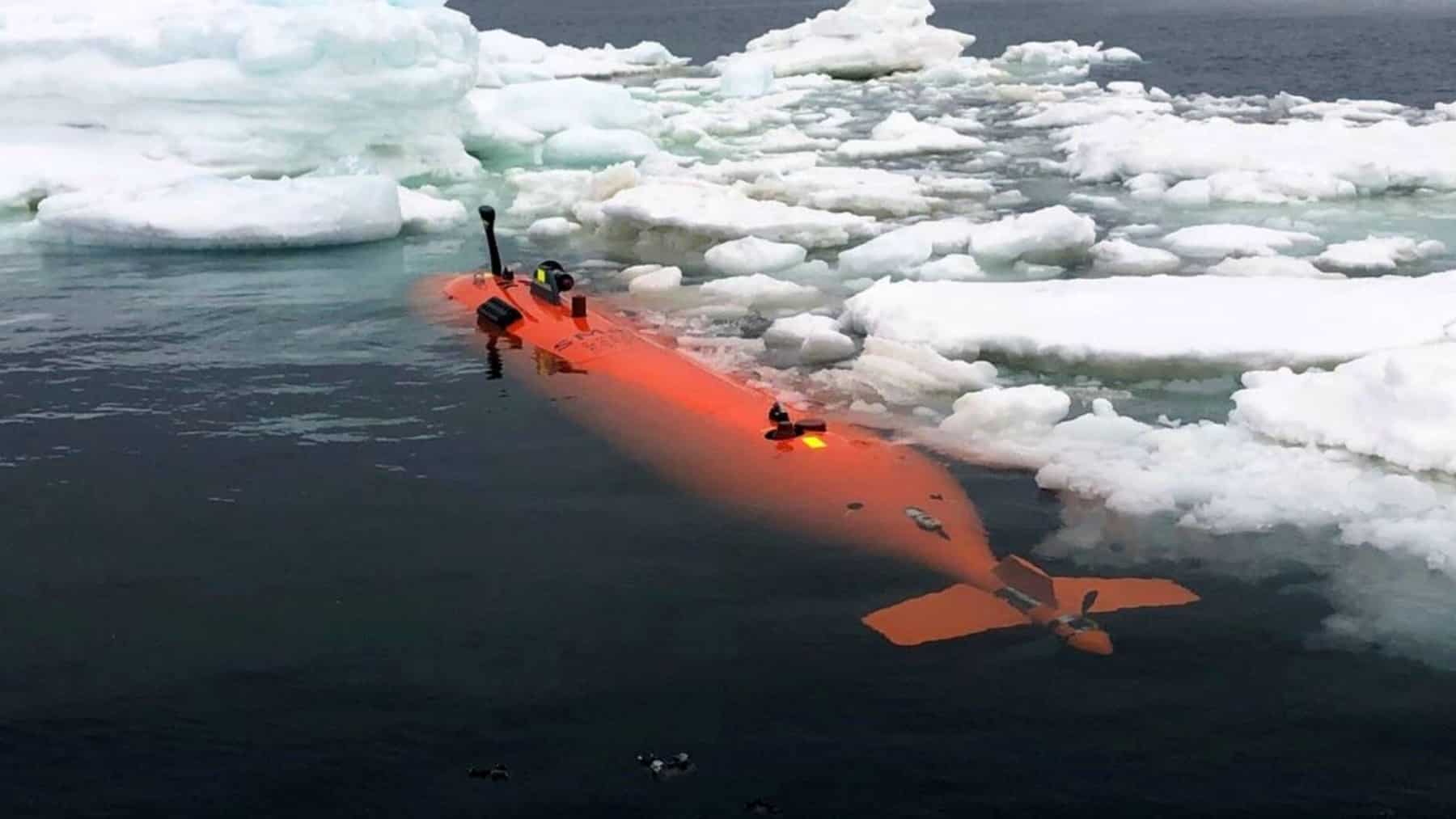 Submarino autónomo naranja navegando entre placas de hielo en el océano Ártico